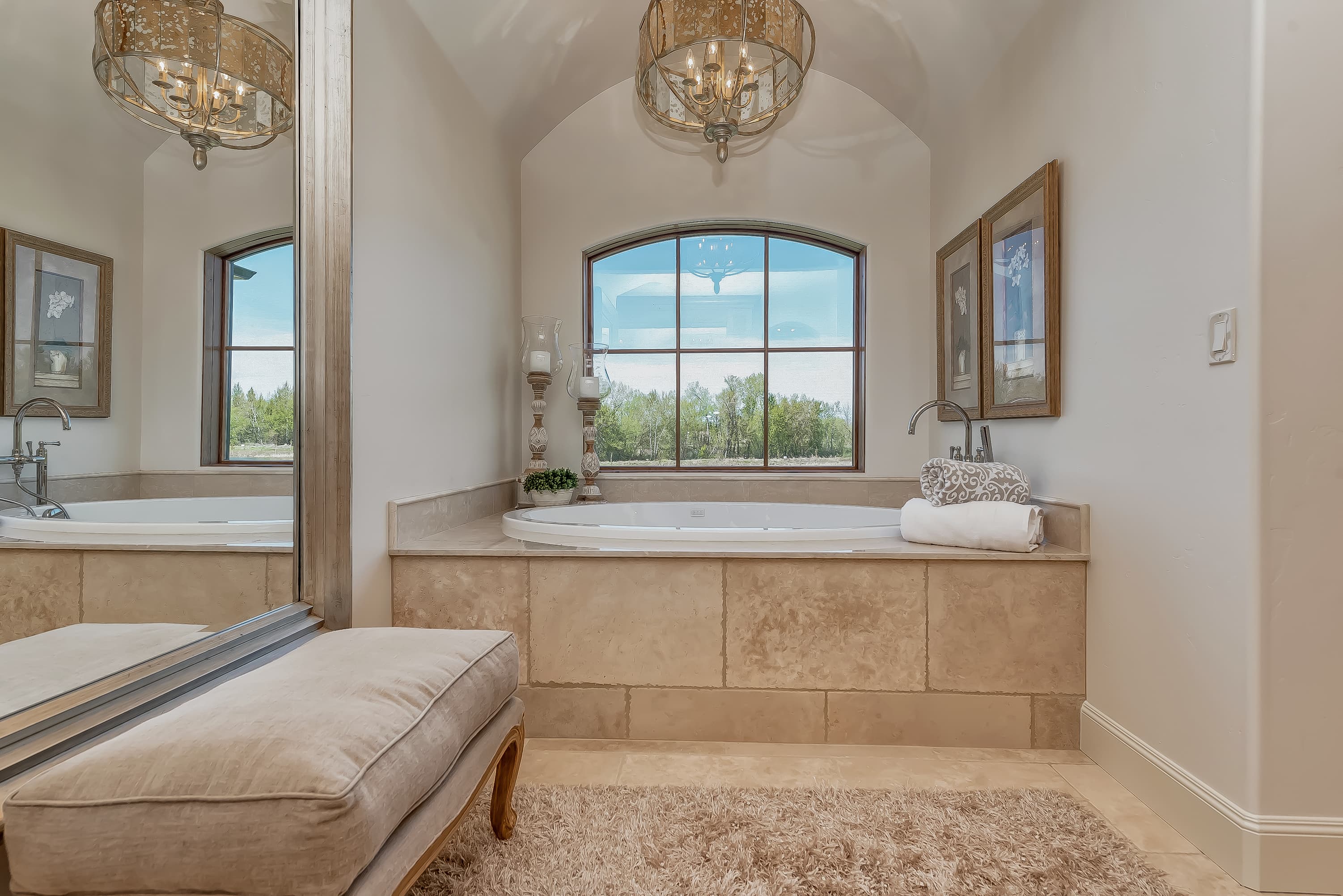 Elegant bathroom with stone tub surround and chandeliers